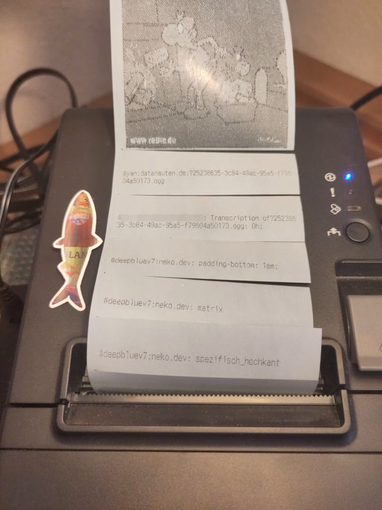 A photo of the receipt printer. Multiple sheets of blue thermopaper with Matrix messages, pictures, and voice messages are coming out of it.